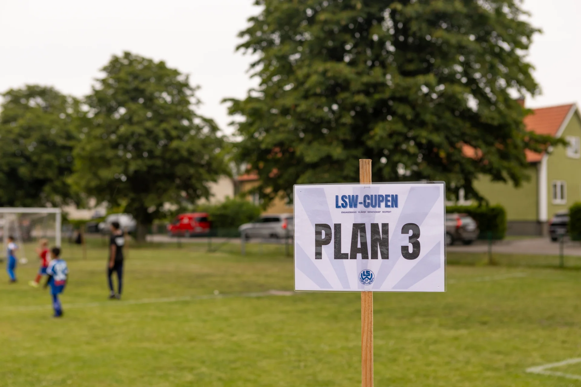 Skylt som visar Plan 3 & en fotbollsplan i bakgrunden. LSW-cupen